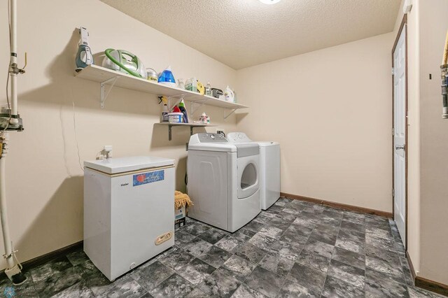 washroom with washer and dryer, a textured ceiling, and baseboards