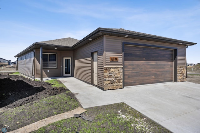 view of front facade featuring concrete driveway, stone siding, and an attached garage