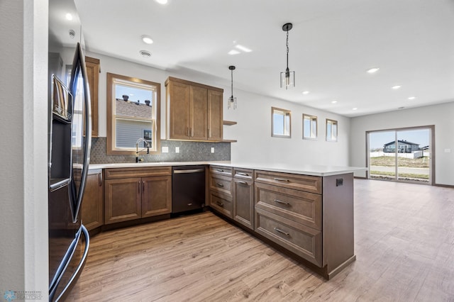 kitchen featuring dishwashing machine, a peninsula, light wood finished floors, tasteful backsplash, and recessed lighting