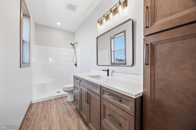 full bathroom with a shower, wood finished floors, toilet, and vanity