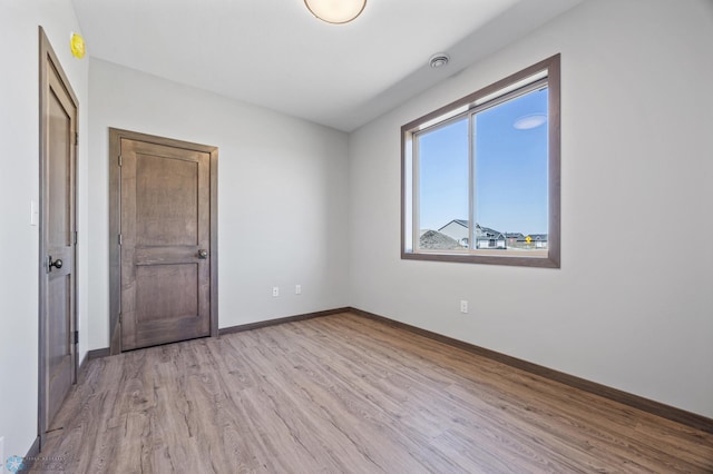 empty room featuring wood finished floors, baseboards, and a smoke detector