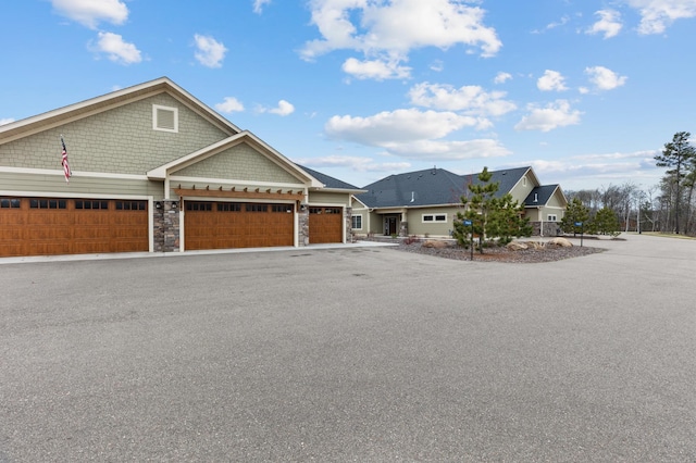 craftsman-style home with a garage, driveway, and stone siding