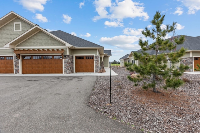 view of front facade with an attached garage, driveway, and stone siding