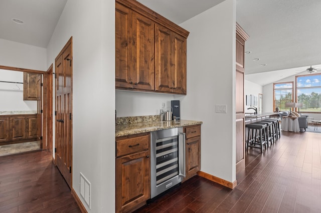 bar with dark wood-style flooring, a ceiling fan, baseboards, lofted ceiling, and wine cooler