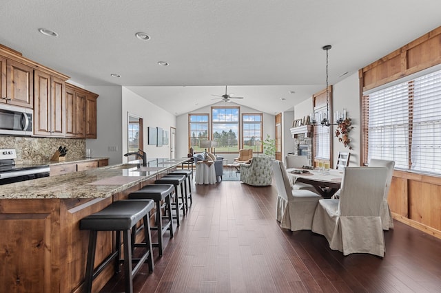 dining space featuring a ceiling fan, dark wood finished floors, and lofted ceiling