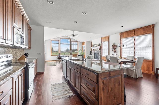 kitchen featuring dark wood-style flooring, appliances with stainless steel finishes, tasteful backsplash, a sink, and baseboards