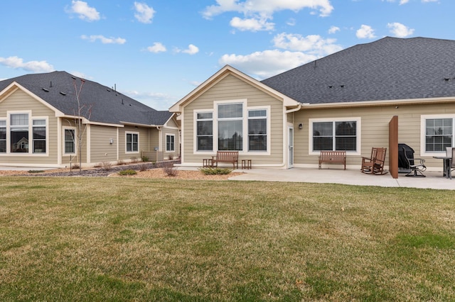 rear view of house with a yard, a patio, and roof with shingles