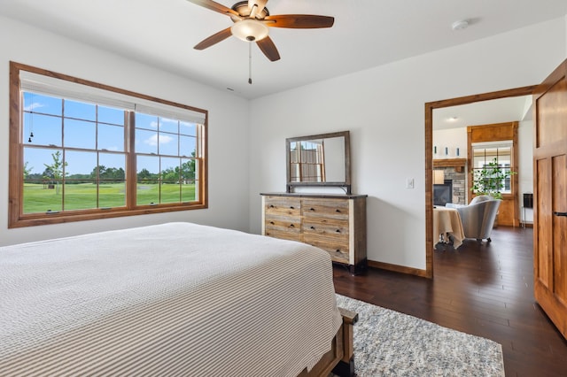 7466 Fairway Ln, Breezy Point, MN 56472 - bedroom with multiple windows, dark wood-style floors, a fireplace, and a ceiling fan