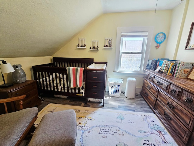 822 4th Ave, Madison, MN 56256 - bedroom featuring a crib, vaulted ceiling, and wood finished floors