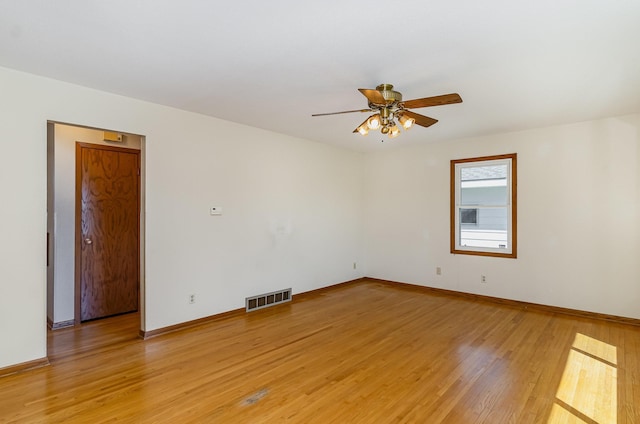empty room featuring baseboards, ceiling fan, light wood finished floors, and visible vents