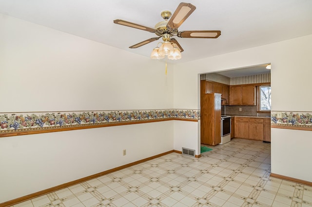 kitchen with electric range, brown cabinetry, a ceiling fan, light floors, and visible vents
