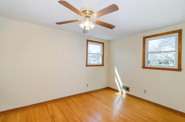 spare room featuring baseboards, a ceiling fan, light wood finished floors, and visible vents