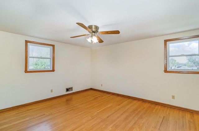 spare room with baseboards, a ceiling fan, light wood finished floors, and visible vents