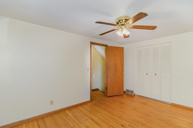 unfurnished bedroom with ceiling fan, visible vents, light wood-type flooring, baseboards, and a closet