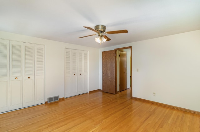 unfurnished bedroom with visible vents, multiple closets, baseboards, a ceiling fan, and light wood-style flooring