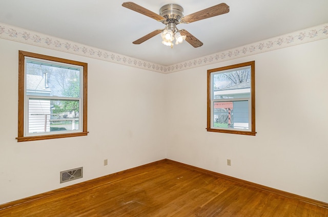unfurnished room featuring a ceiling fan, baseboards, visible vents, and wood finished floors