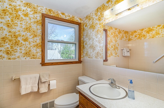 bathroom featuring vanity, a wainscoted wall, toilet, and wallpapered walls