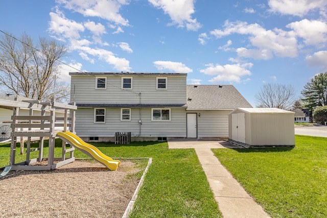 rear view of property featuring a yard, an outdoor structure, a playground, and a storage unit