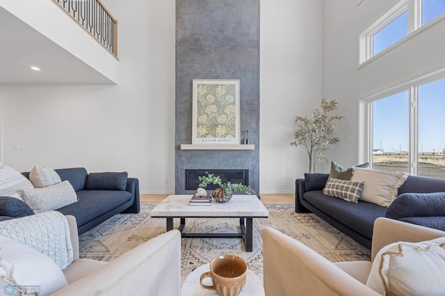 living area featuring baseboards, a fireplace, wood finished floors, and a towering ceiling