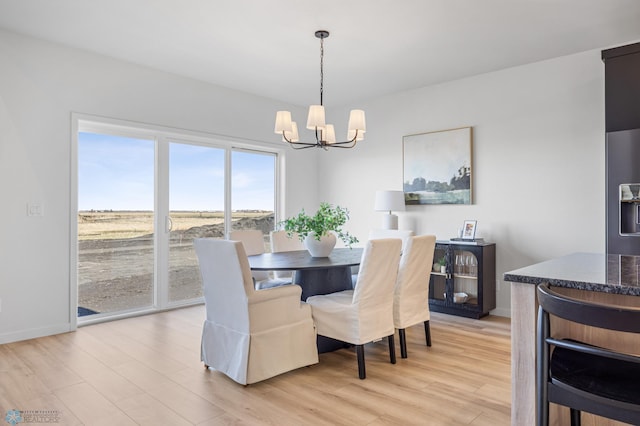 dining area featuring baseboards, a chandelier, and light wood-style flooring