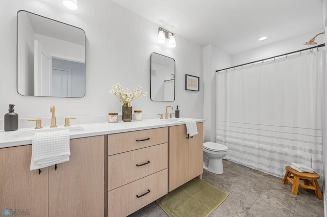 bathroom with double vanity, a sink, a shower with shower curtain, and toilet