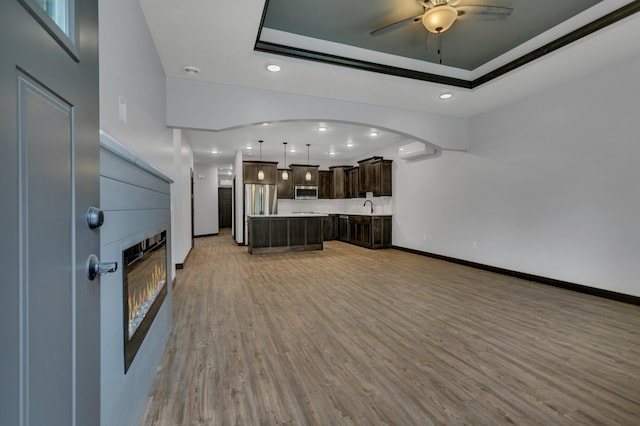 215 Butler St, Litchfield, MN 55355 - unfurnished living room featuring a glass covered fireplace, a ceiling fan, light wood-style flooring, recessed lighting, and an AC wall unit