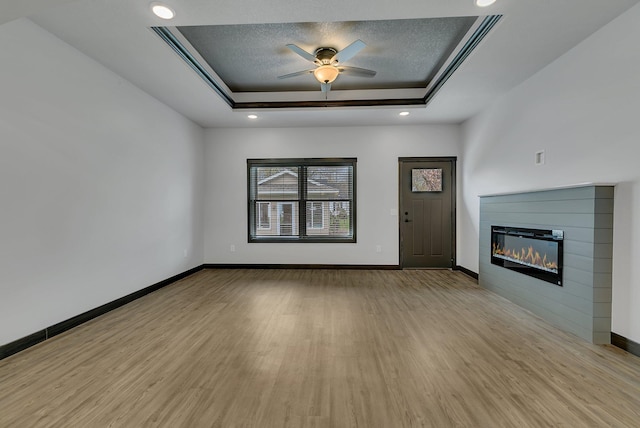 215 Butler St, Litchfield, MN 55355 - unfurnished living room with a tray ceiling, wood finished floors, ceiling fan, a glass covered fireplace, and recessed lighting