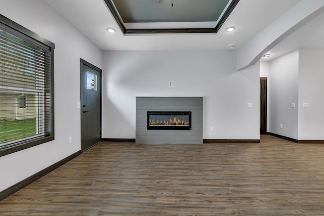 215 Butler St, Litchfield, MN 55355 - unfurnished living room with recessed lighting, wood finished floors, a glass covered fireplace, arched walkways, and a raised ceiling