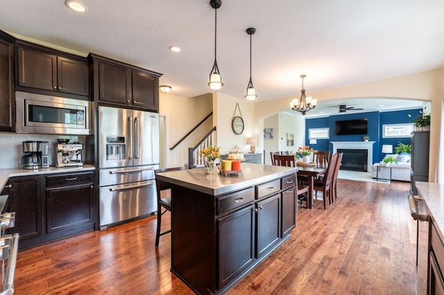 19717 Hazel Nut Ave, Lakeville, MN 55044 - kitchen featuring stainless steel appliances, arched walkways, hardwood / wood-style floors, open floor plan, and decorative light fixtures