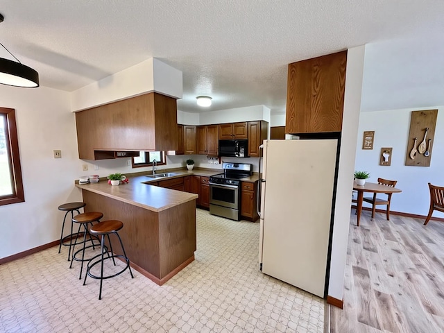 777 Big Round Ave, Georgetown Twp, WI 54853 - kitchen featuring black microwave, stainless steel electric range, a sink, freestanding refrigerator, and a peninsula