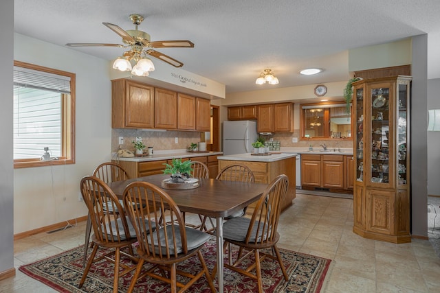 dining space with a ceiling fan, baseboards, and a textured ceiling