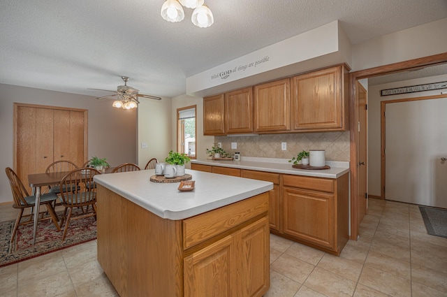 kitchen with light countertops, a kitchen island, tasteful backsplash, a textured ceiling, and ceiling fan
