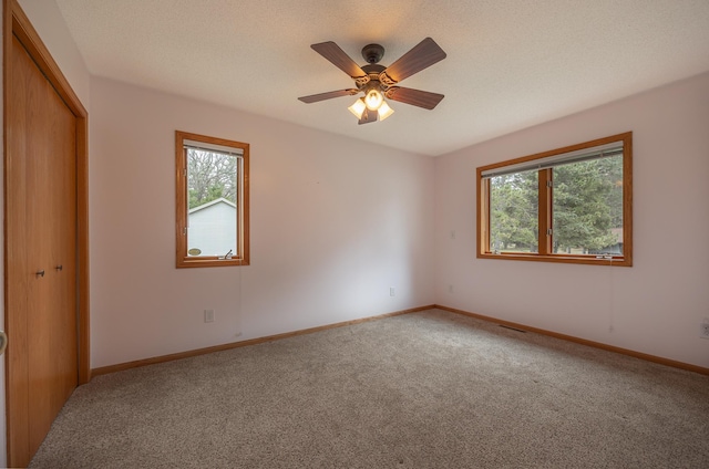 carpeted spare room with plenty of natural light, baseboards, and a ceiling fan