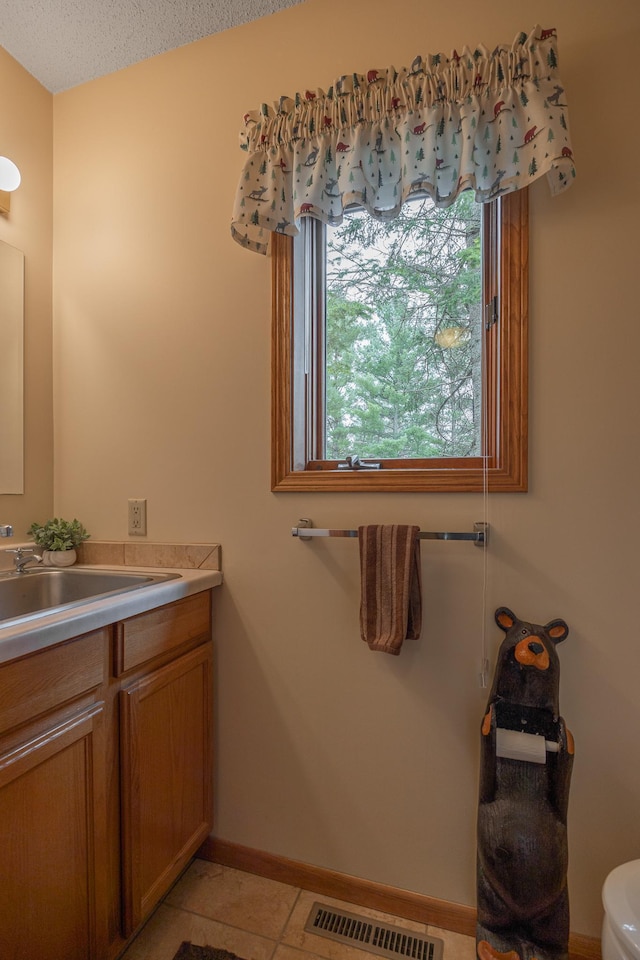 bathroom featuring vanity, baseboards, toilet, and tile patterned floors