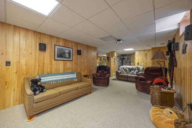 living area with carpet, wooden walls, and a drop ceiling