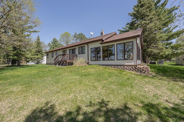 rear view of property with a yard, a chimney, and a wooden deck