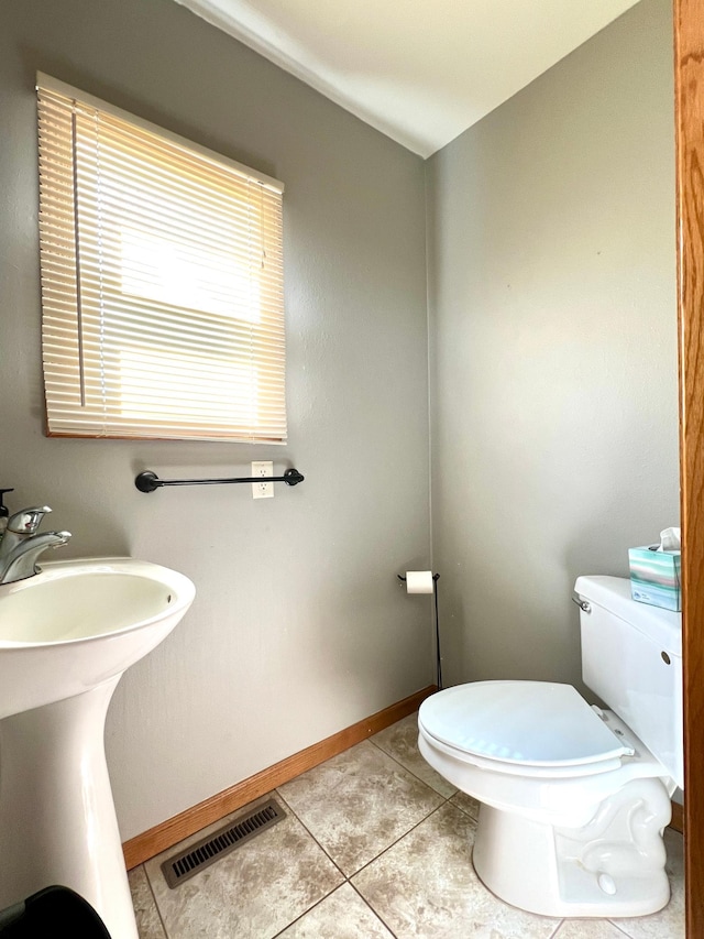 bathroom featuring a sink, tile patterned flooring, toilet, baseboards, and visible vents