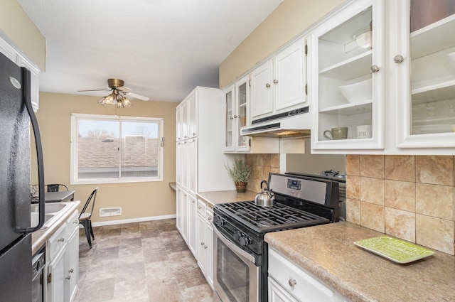 kitchen with freestanding refrigerator, stainless steel range with gas cooktop, under cabinet range hood, white cabinets, and a ceiling fan