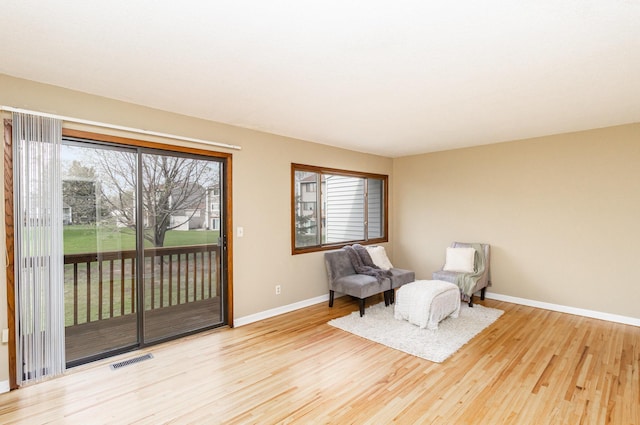 living area featuring baseboards, wood finished floors, and visible vents