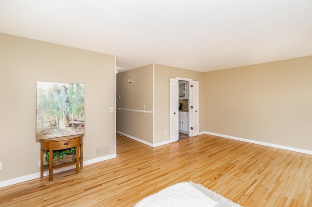 unfurnished room with baseboards, light wood finished floors, and visible vents