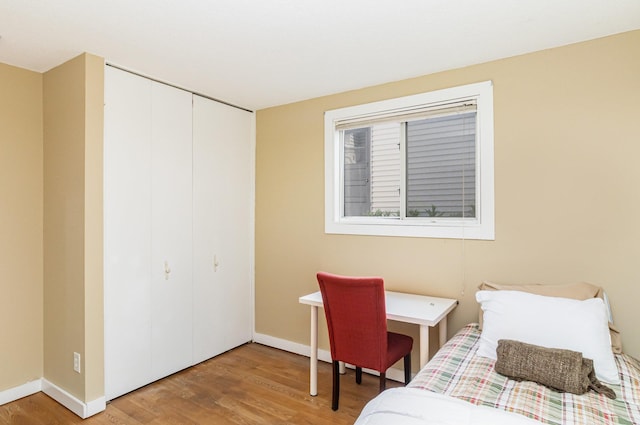 bedroom with a closet, light wood finished floors, and baseboards
