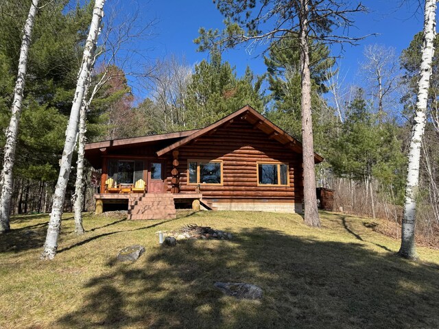 rear view of property with a lawn and log siding