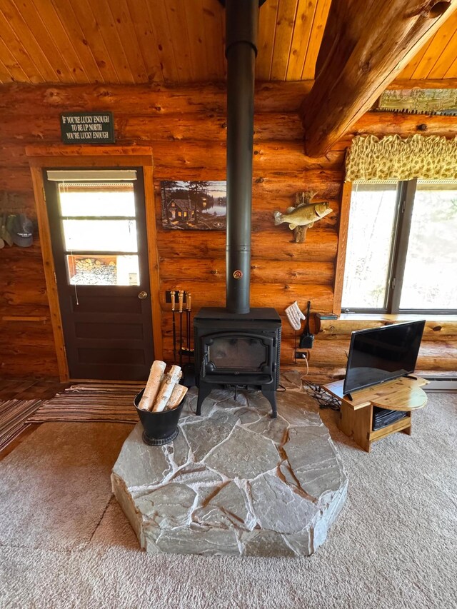 carpeted living room with a wood stove, log walls, and a wealth of natural light
