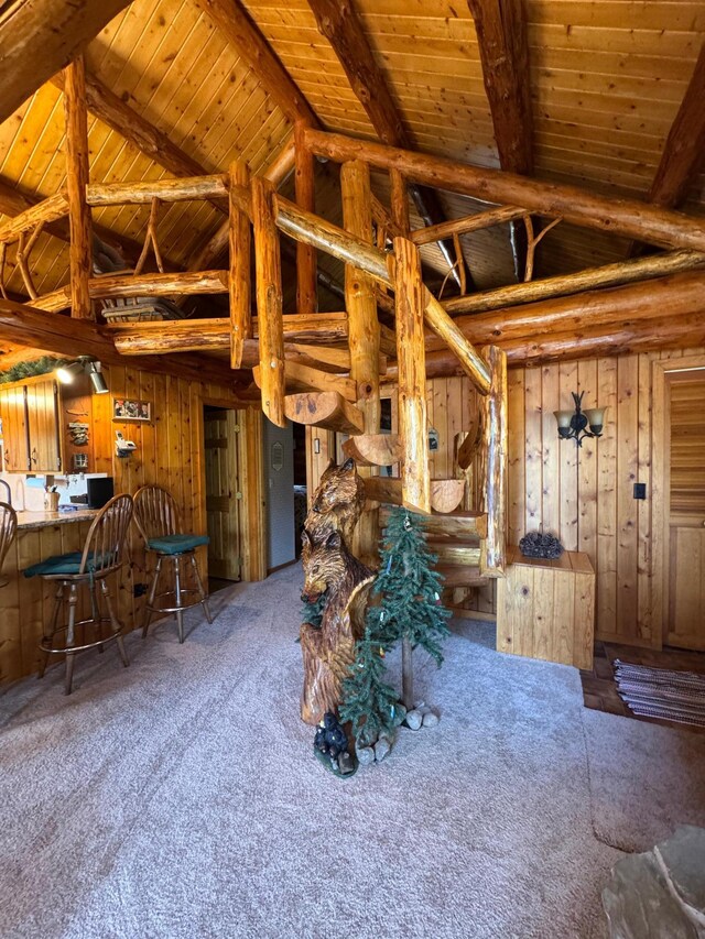 carpeted living room featuring wooden walls, high vaulted ceiling, and wooden ceiling