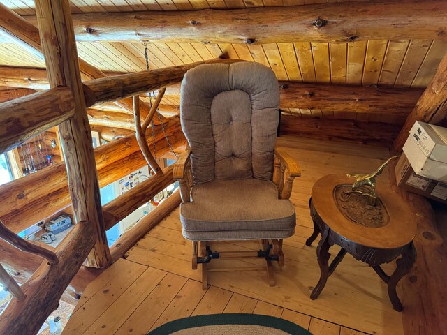 sitting room with rustic walls, wooden ceiling, beamed ceiling, and light wood-style flooring