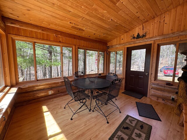 dining space with wood ceiling, vaulted ceiling, wood walls, and light wood-style flooring