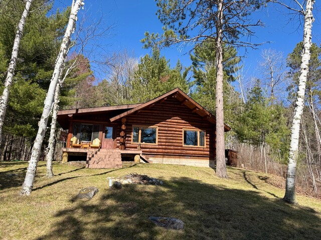 back of property featuring a yard and log siding