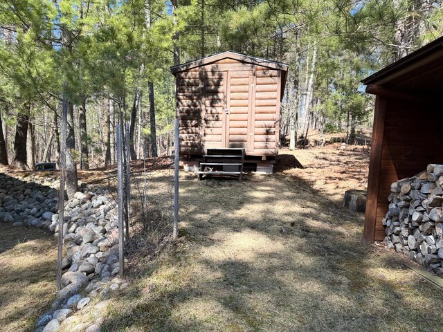 view of yard with an outdoor structure, a view of trees, and a storage shed