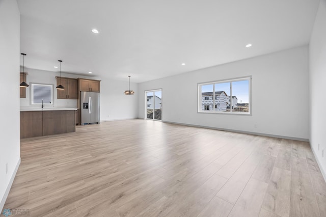 8343 61st St S, Horace, ND 58047 - unfurnished living room with light wood-style flooring, recessed lighting, and a chandelier