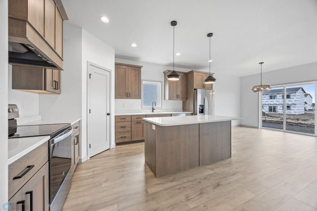 8343 61st St S, Horace, ND 58047 - kitchen with stainless steel appliances, wall chimney range hood, a center island, light countertops, and light wood-style flooring